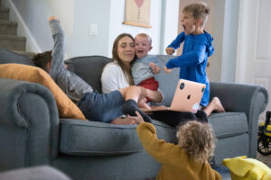 Amanda Jones working while having a chaos filled couch of four children.